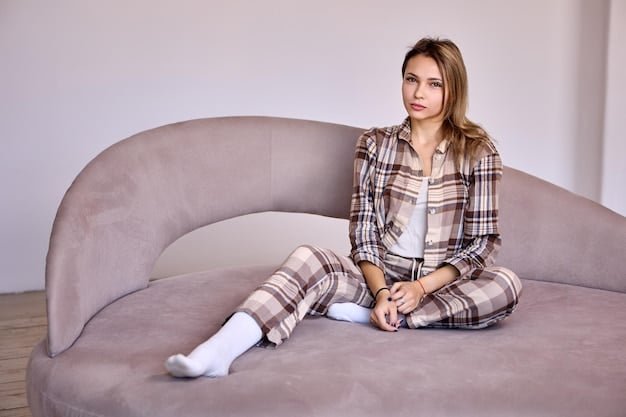 A woman is sitting comfortably on a plush sofa, wearing a silky Shein pajama set in a deep emerald green color, holding a book. The room is softly lit, with a focus on the luxurious feel of the pajamas and the relaxed atmosphere.