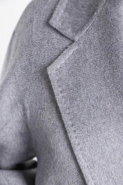 A close-up shot of a Shein blazer's fabric, showcasing a subtle texture and quality stitching. The blazer is a muted gray color, suggesting versatility and professionalism.