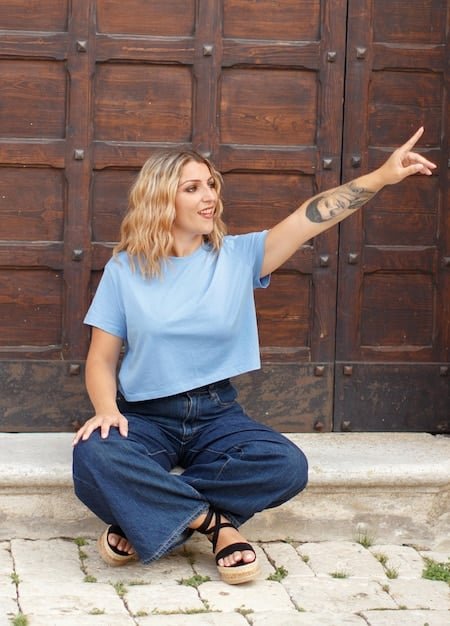 A plus-size woman wearing a Shein graphic tee with high-waisted jeans. She is accessorized with a crossbody bag and white sneakers. The background is an urban street setting, showcasing the casual and chic vibe of the outfit.