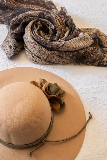 A close-up shot of a curated selection of accessories, including a neutral-colored scarf, a simple gold necklace, a black belt, and a pair of classic ankle boots, laid out on a soft, neutral background.