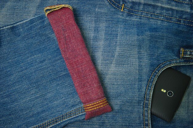A close-up of a Shein jeans size chart on a mobile device, highlighting the different measurements (waist, hips, inseam) and their corresponding sizes. The fingers are pointing to specific measurements as if guiding the viewer.