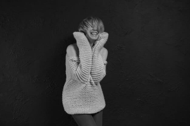 A grayscale image showcasing various textures and shades of gray in a modern outfit. It includes a light gray cashmere sweater, dark charcoal wool trousers, and silver metallic accessories, highlighting how different textures and shades can create depth within a monochrome look.