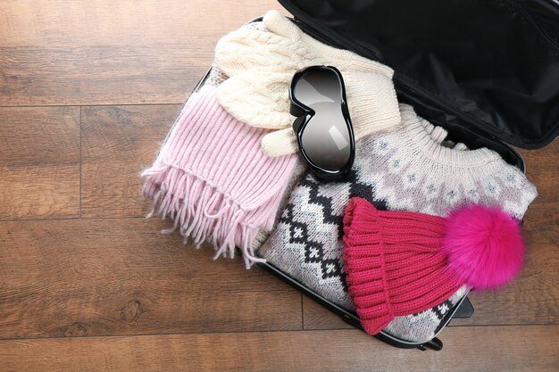 Close-up of a suitcase packed with colorful, lightweight clothing items from Shein. Pieces include a floral-print top, denim shorts, a striped swimsuit, and a variety of accessories like scarves and jewelry. The arrangement shows how to maximize space and coordinate outfits.