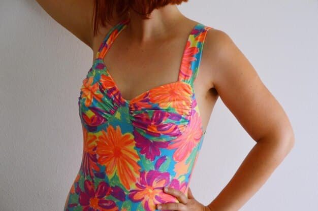 A close-up shot of a Shein swimsuit featuring a vibrant tropical print. The swimsuit is displayed on a sandy background with a few seashells scattered around. The focus is on the details of the print, showcasing the bright colors and intricate design.